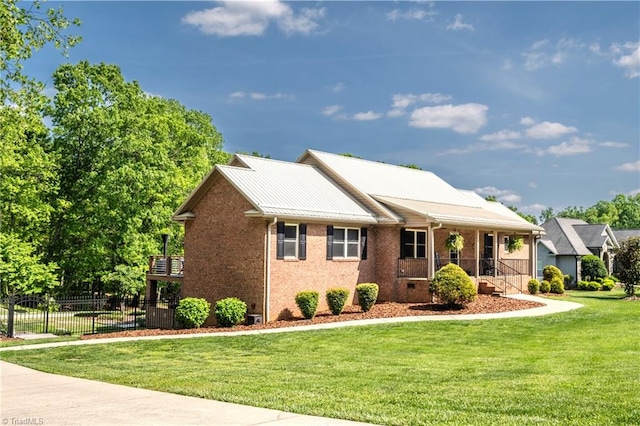 view of front facade featuring a porch, fence, a front lawn, and brick siding