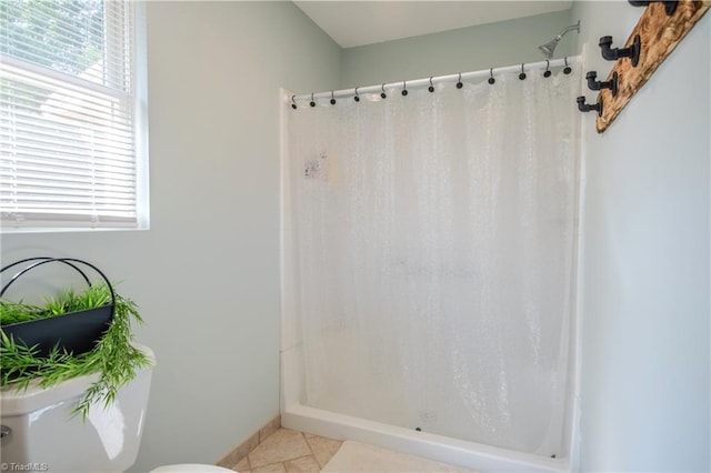 bathroom with toilet, a shower with shower curtain, tile patterned flooring, and baseboards