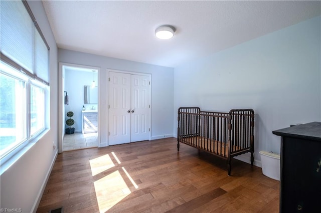 bedroom with baseboards, a closet, visible vents, and wood finished floors