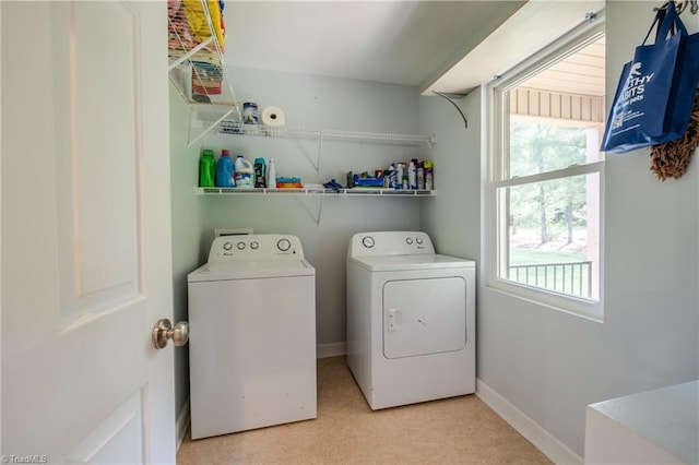 clothes washing area featuring separate washer and dryer, laundry area, plenty of natural light, and baseboards