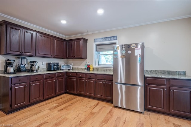 kitchen with freestanding refrigerator, ornamental molding, dark brown cabinets, and light wood-style floors