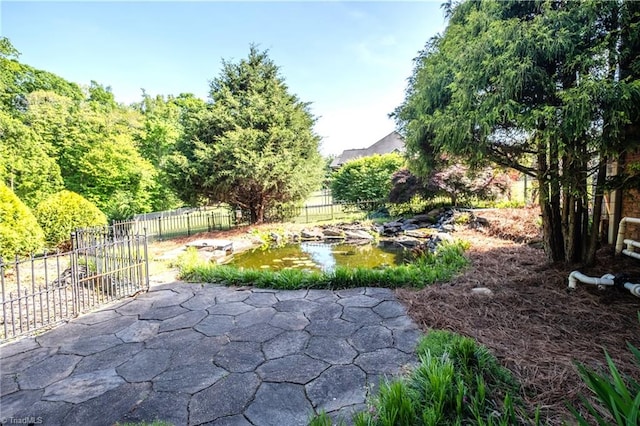 exterior space featuring a garden pond, a patio, and fence