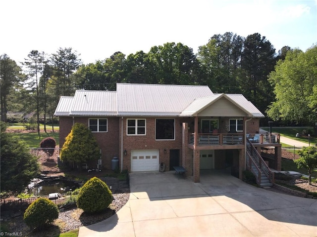 rear view of house featuring concrete driveway, stairway, brick siding, and an attached garage