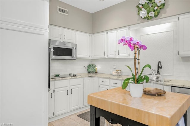 149 Warwicke Pl, Bermuda Run, NC 27006 - kitchen with stainless steel microwave, backsplash, light countertops, and white cabinets