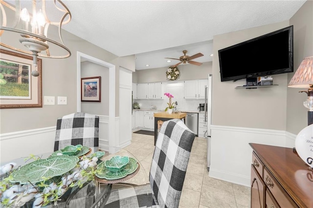 149 Warwicke Pl, Bermuda Run, NC 27006 - dining area featuring a ceiling fan, a chandelier, light tile patterned flooring, a textured ceiling, and a wainscoted wall
