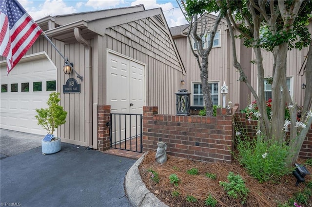 149 Warwicke Pl, Bermuda Run, NC 27006 - view of property exterior with an attached garage, asphalt driveway, board and batten siding, and brick siding