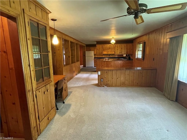 1706 Windsor Dr, High Point, NC 27262 - kitchen with freestanding refrigerator, brown cabinetry, light colored carpet, wood walls, and a peninsula