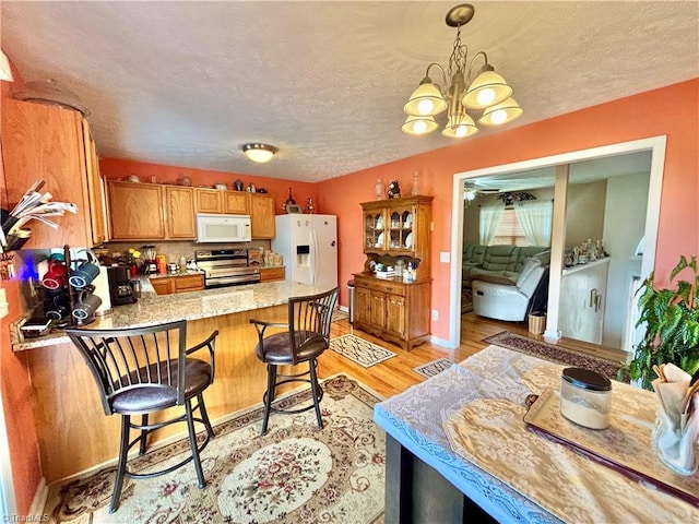 155 Page Farm Rd, Mount Airy, NC 27030 - kitchen with a peninsula, brown cabinetry, white appliances, a textured ceiling, and light wood-type flooring