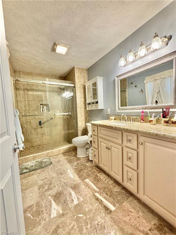 155 Page Farm Rd, Mount Airy, NC 27030 - full bathroom featuring vanity, toilet, a stall shower, and a textured ceiling