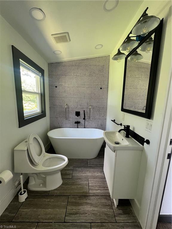 2042 Harrison Ave, Winston-Salem, NC 27105 - full bath featuring a freestanding bath, vanity, and wood finish floors
