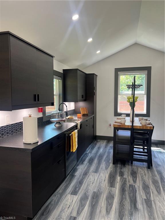 2042 Harrison Ave, Winston-Salem, NC 27105 - kitchen with dark cabinets, dark countertops, vaulted ceiling, dark wood-style flooring, and plenty of natural light