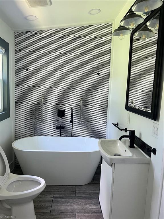 2042 Harrison Ave, Winston-Salem, NC 27105 - full bathroom with vanity, a freestanding tub, and wood finished floors
