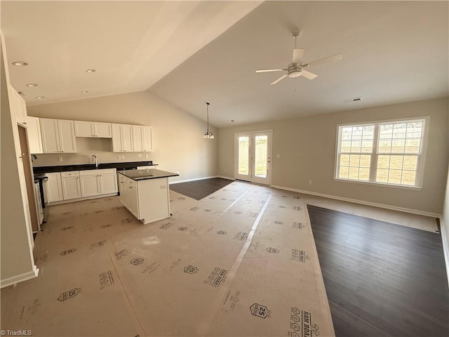 kitchen featuring white cabinetry, open floor plan, hanging light fixtures, a center island, and dark countertops