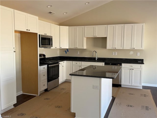 kitchen featuring visible vents, white cabinets, a center island, vaulted ceiling, and stainless steel appliances