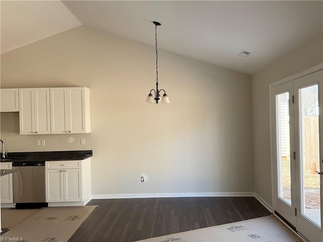 kitchen featuring dark countertops, white cabinetry, stainless steel dishwasher, and decorative light fixtures