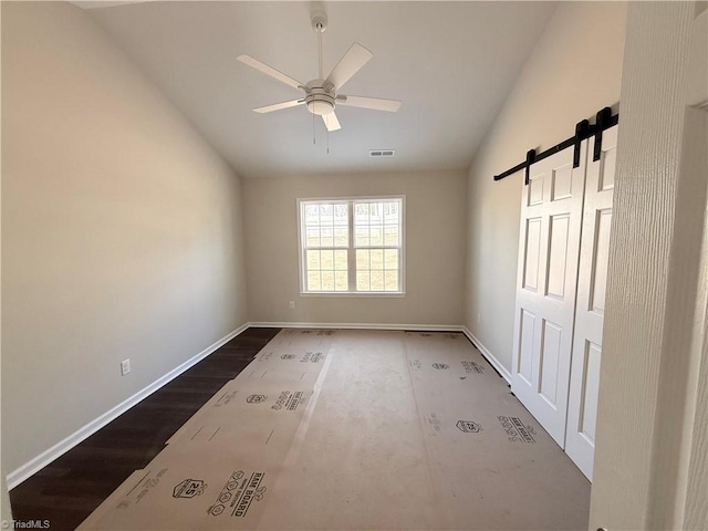 unfurnished room featuring a barn door, visible vents, baseboards, lofted ceiling, and ceiling fan