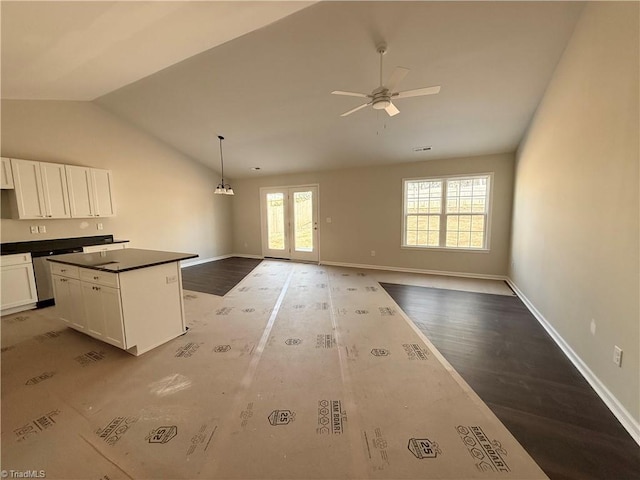 kitchen with dark countertops, open floor plan, white cabinetry, and a kitchen island