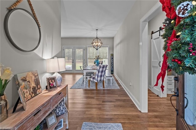 dining space featuring hardwood / wood-style flooring, a chandelier, a barn door, and french doors