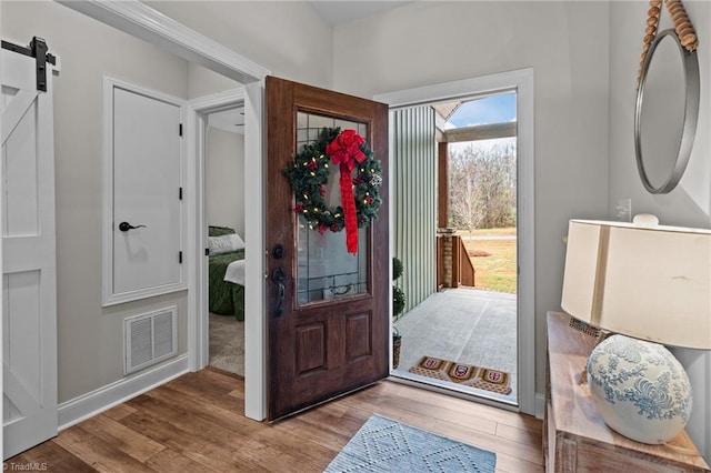 foyer entrance with light wood-type flooring and a barn door