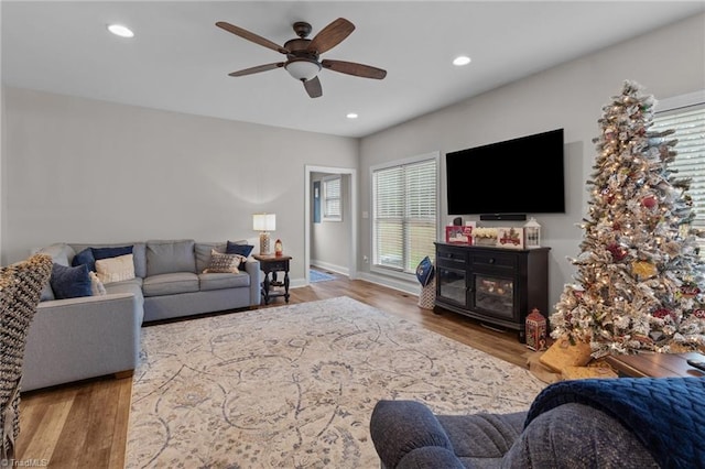 living room with a fireplace, light hardwood / wood-style floors, and ceiling fan