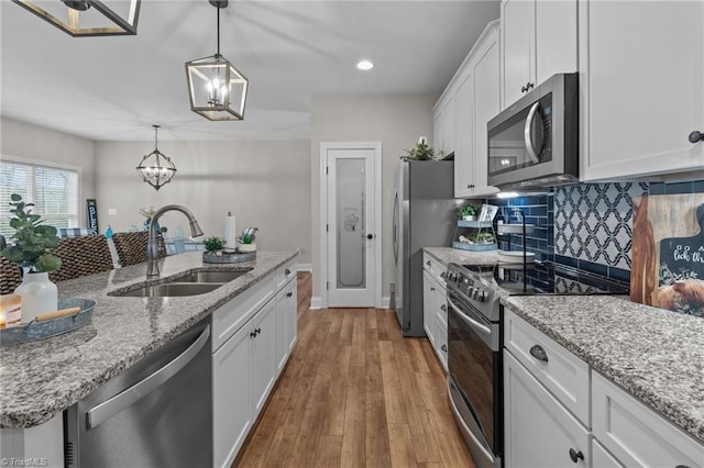 kitchen with pendant lighting, sink, light wood-type flooring, appliances with stainless steel finishes, and white cabinetry