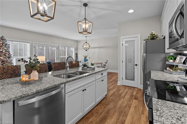 kitchen with white cabinetry, sink, hanging light fixtures, and appliances with stainless steel finishes