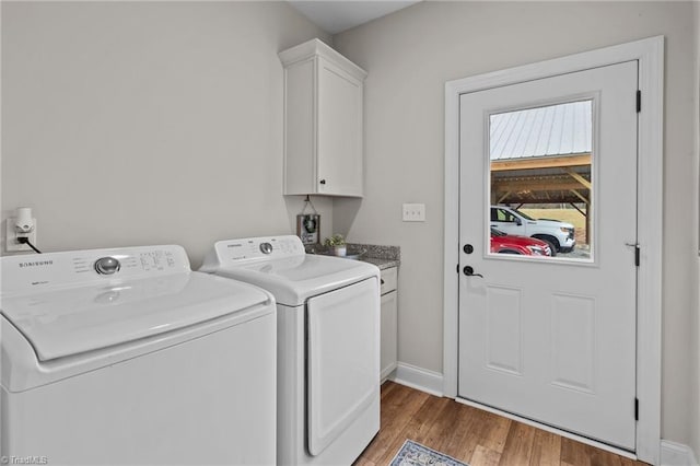 laundry area featuring washer and clothes dryer, hardwood / wood-style floors, and cabinets