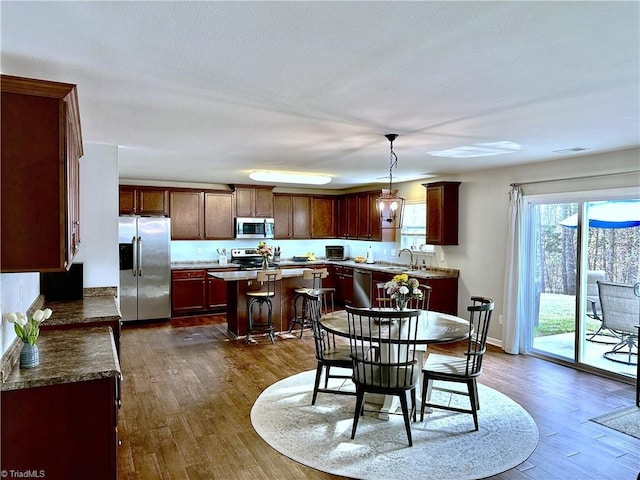 kitchen with a center island, stainless steel appliances, dark hardwood / wood-style flooring, decorative light fixtures, and sink