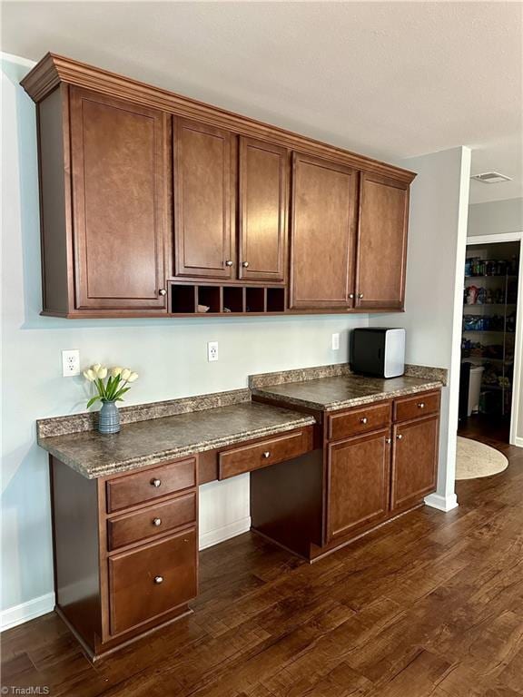 kitchen with dark wood-type flooring and built in desk