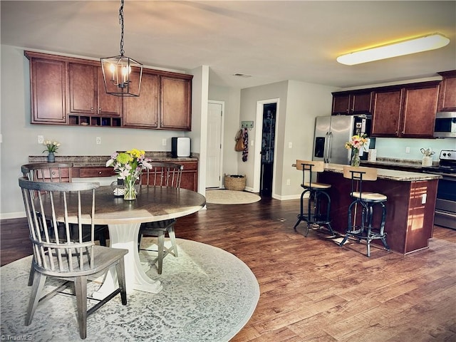 kitchen featuring dark hardwood / wood-style flooring, a kitchen island, stainless steel appliances, and a kitchen bar