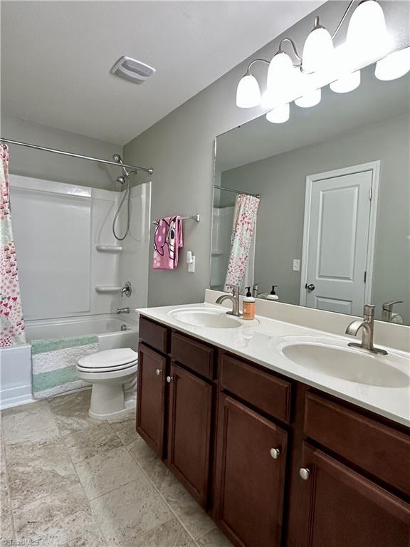 full bathroom with shower / bath combination with curtain, vanity, and toilet