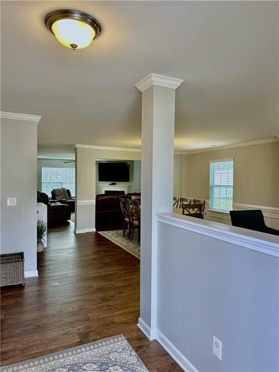 hallway with decorative columns, dark hardwood / wood-style floors, and ornamental molding