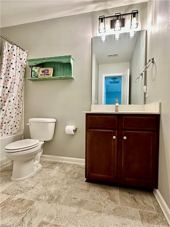 full bathroom with vanity, shower / tub combo with curtain, and toilet