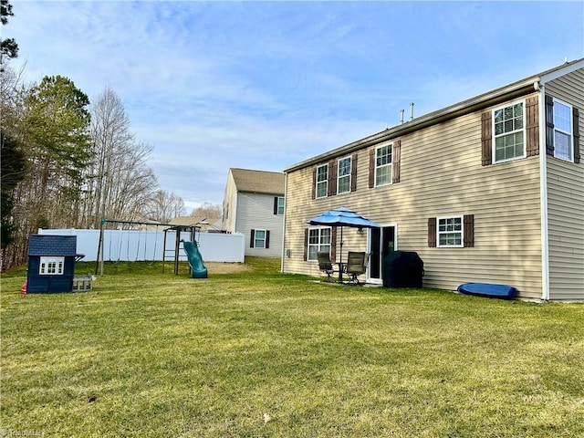 rear view of property with a playground and a yard