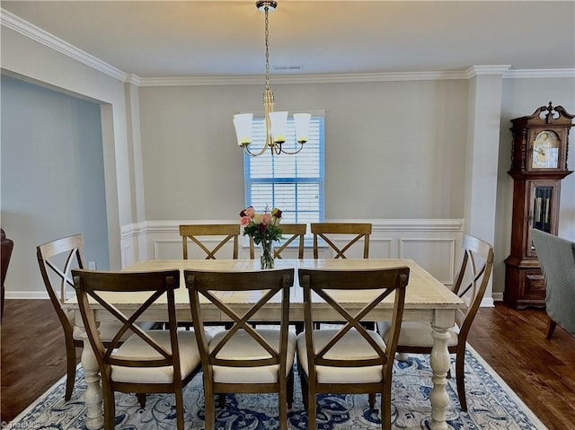 dining area with ornamental molding, dark wood-type flooring, and a chandelier