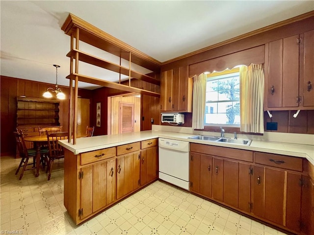 kitchen featuring a sink, a peninsula, white dishwasher, light countertops, and light floors