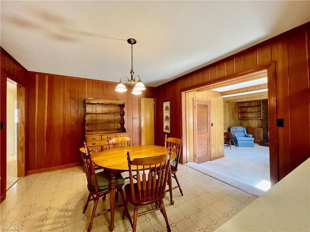 dining area with light floors, wood walls, and a chandelier