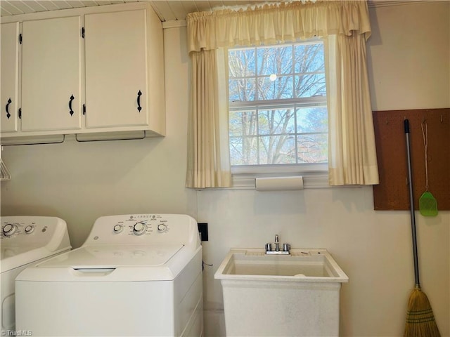 clothes washing area featuring cabinet space, washing machine and dryer, and a sink