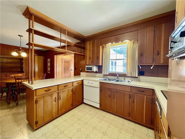 kitchen with light floors, a peninsula, a sink, light countertops, and dishwasher