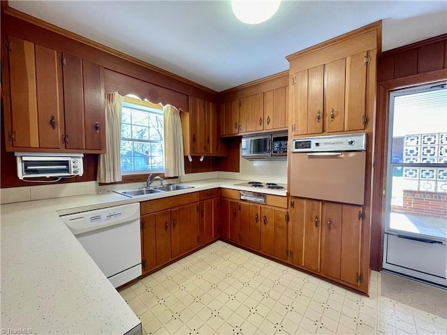 kitchen featuring white appliances, light floors, light countertops, and a sink