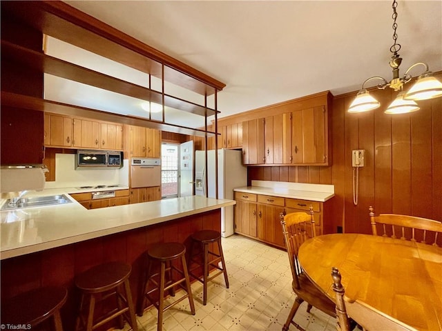 kitchen with stainless steel microwave, oven, light floors, light countertops, and a sink