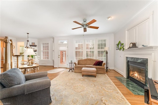 living room with ornamental molding, light wood-type flooring, ceiling fan, and a fireplace