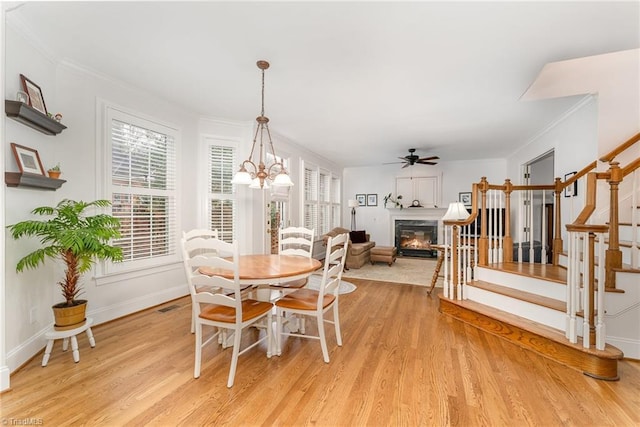 dining space with ceiling fan with notable chandelier, ornamental molding, and light hardwood / wood-style floors