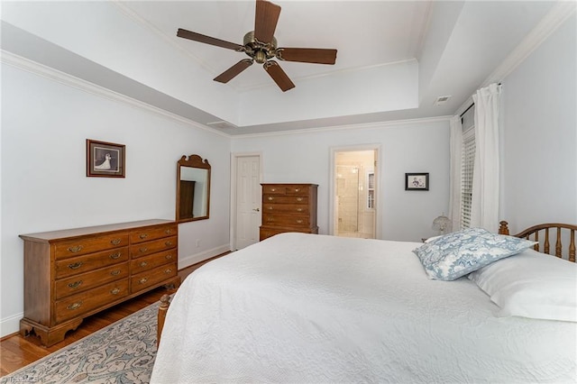 bedroom featuring a tray ceiling, wood-type flooring, and ornamental molding