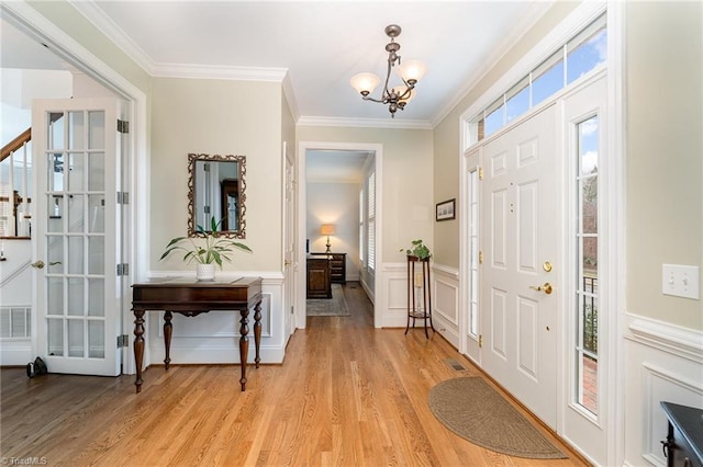 entrance foyer with ornamental molding, a chandelier, and light wood-type flooring