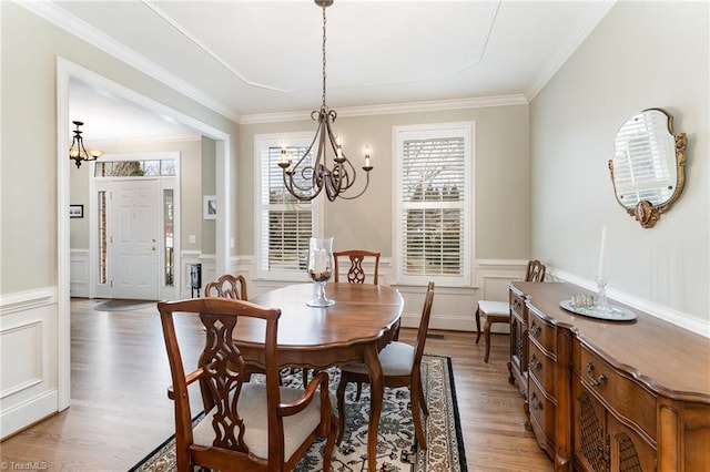 dining area featuring hardwood / wood-style flooring, plenty of natural light, crown molding, and an inviting chandelier