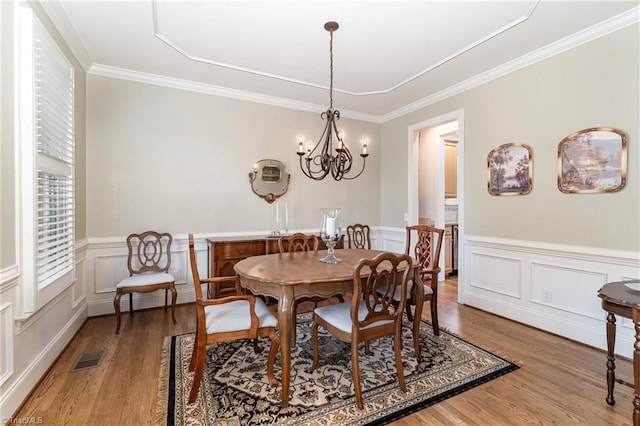 dining area with an inviting chandelier, crown molding, and light hardwood / wood-style flooring