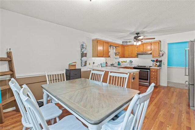 dining room with a textured ceiling, sink, ceiling fan, and light hardwood / wood-style floors