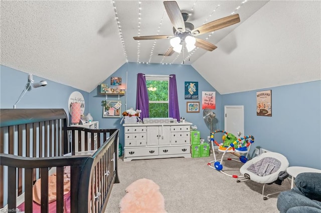 bedroom with a textured ceiling, vaulted ceiling, carpet, ceiling fan, and a nursery area