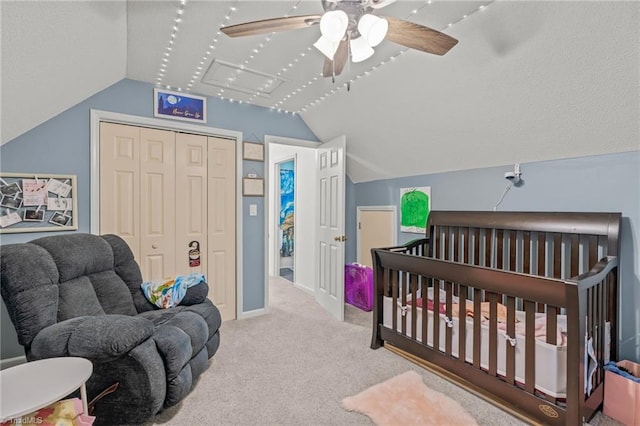 bedroom with a closet, carpet, a crib, and vaulted ceiling